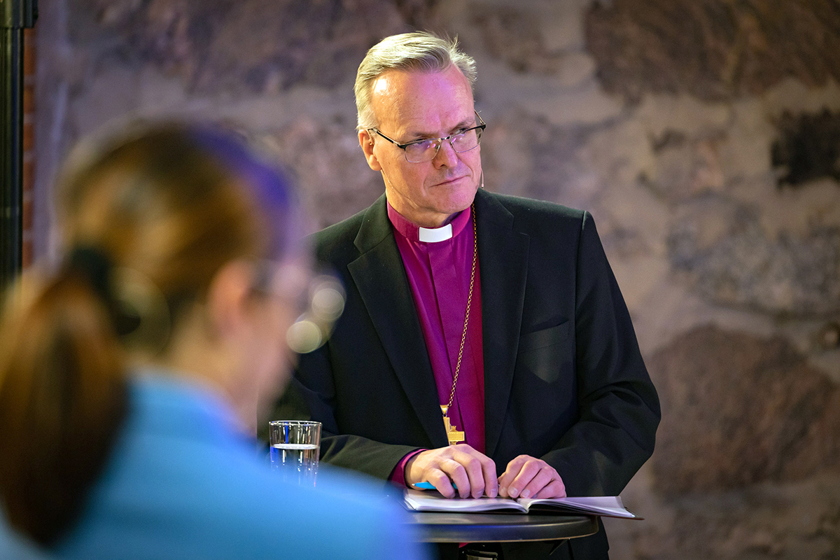 Ärkebiskop står bakom ett bord.