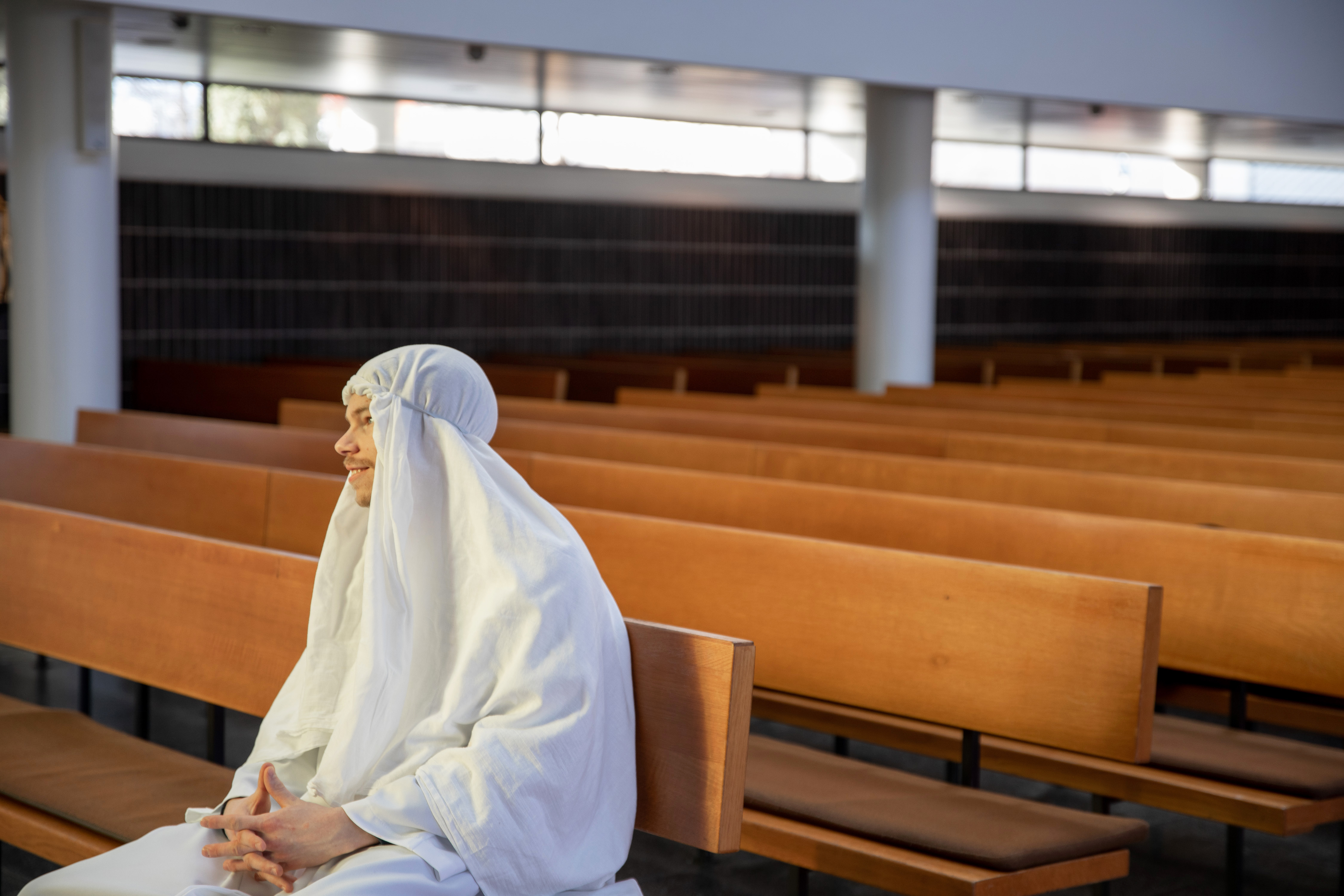 Jesus sitter ensam in kyrkbänk.